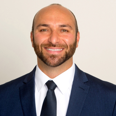 Headshot of Brad Sforza wearing a navy blue suit, white shirt, and navy blue tie