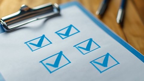 blue clipboard with checked boxes on top of a desk