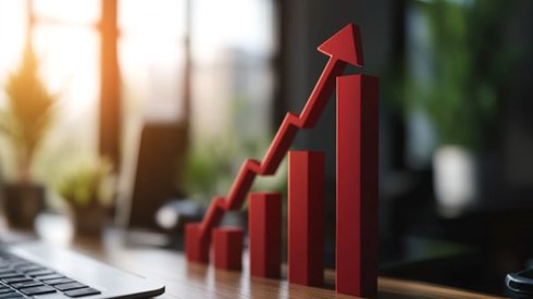 red bar graph with arrow going up sitting on desk