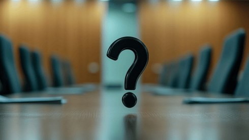 A black question mark hovering over a conference table surrounded by empty chairs