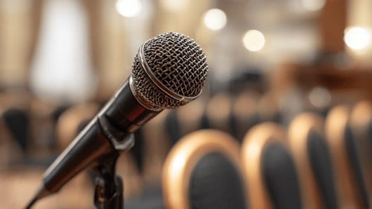 A microphone in front of empty chairs at a conference