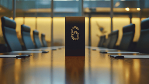 The number six standing up in the middle of a conference table that is surrounded by chairs