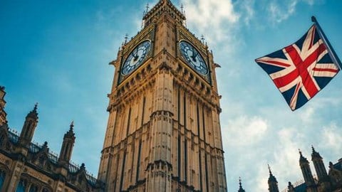 UK parliament building clock tower next to the UK flag flying on a pole