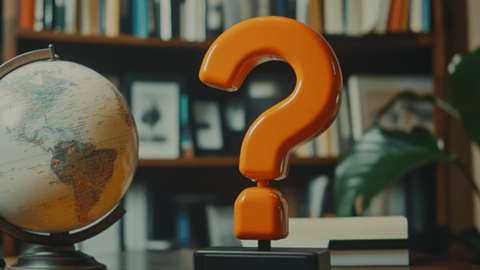 An orange question mark next to a globe with both sitting on an office desk