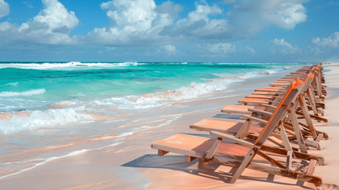 A row of wood-framed orange canvas beach chairs on a beach with pink sand in Bermuda