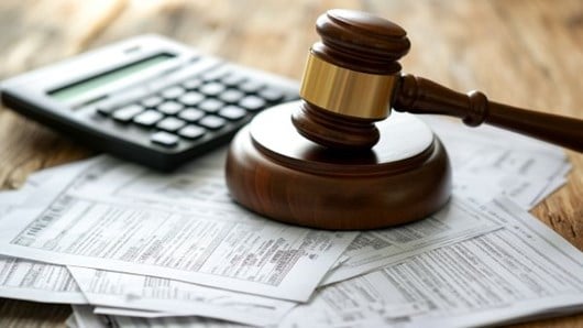 gavel on a stack of financial papers next to a calculator