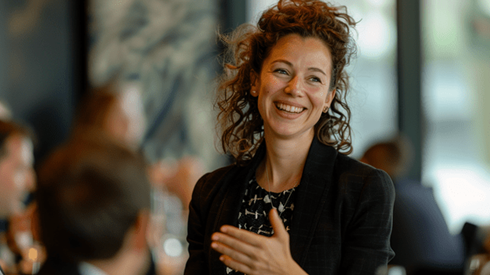 A businesswoman smiles while talking to seated coworkers in an office