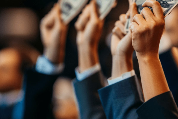 Businesspeople in suits holding up money