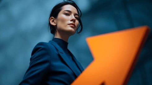 A businesswoman wearing a dark blue suit next to a bright orange arrow