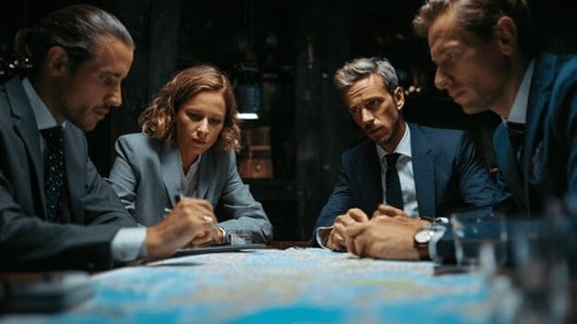 Four risk managers sitiing around a map discussing strategy