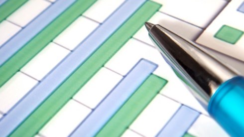 Bar chart with blue and green columns on white paper with blue pen pointing to a green bar