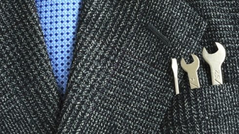 Closeup of businessman´s tie and jacket pocket containing a flat head screwdriver and two different sized wrenches