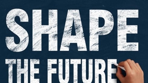 Business professional with chalk putting finishing touch on the words SHAPE THE FUTURE written on a blackboard