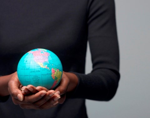 A woman of color holding a small globe in the palms of her hands