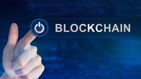 Finger selecting blockchain power button with blue digital background