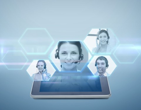 A tablet with virtual screens floating above it showing several businesspeople with headphones