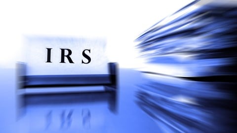 IRS written on a sign next to a big stack of papers