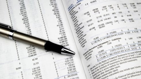 Two pages open on a printed and bound annual investment report with a black and silver pen sitting on top