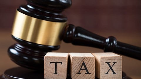 Gavel and base behind three building blocks that spell the word TAX