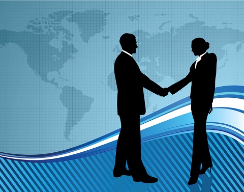 Silhouette of a man and woman shaking hands in front of world map