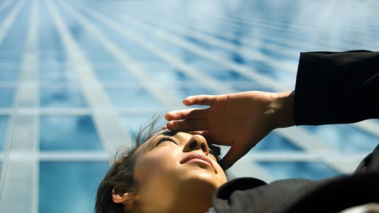 Businesswoman looking into the distance with office building behind her